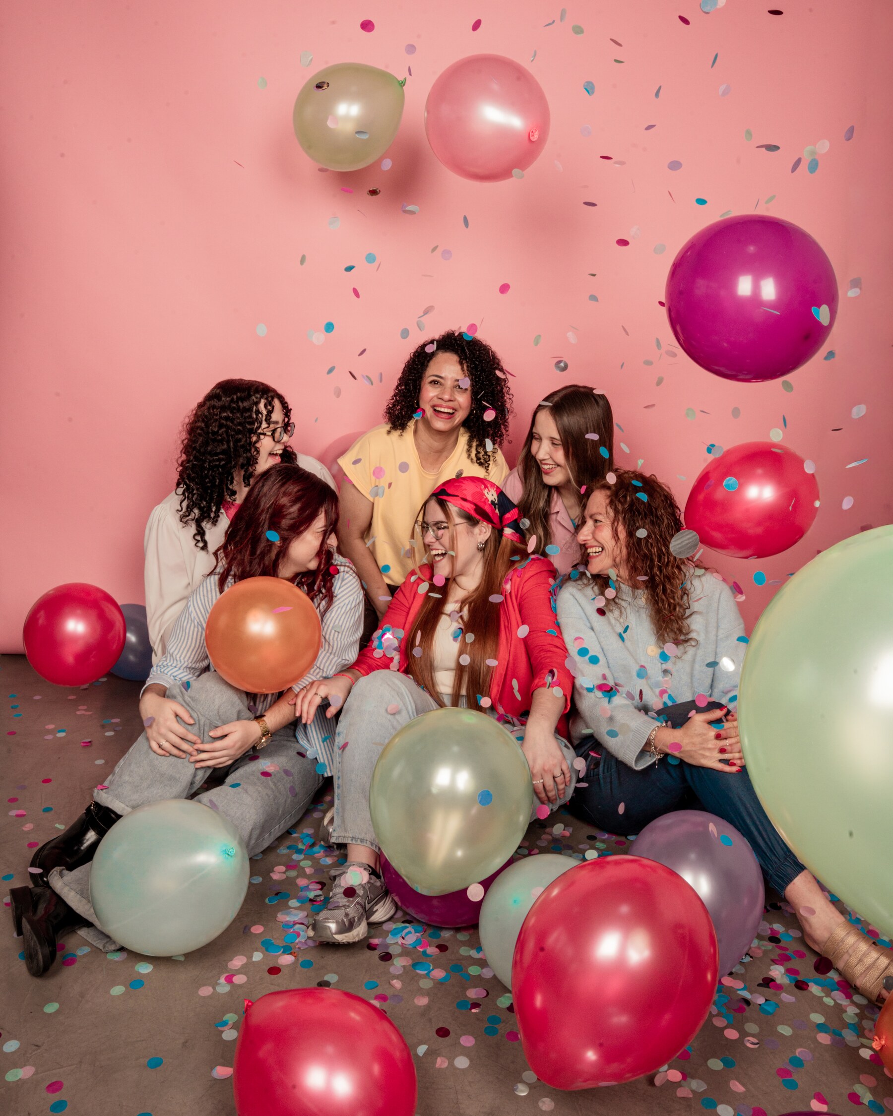 Grupo de mujeres celebrando juntas entre globos y confeti